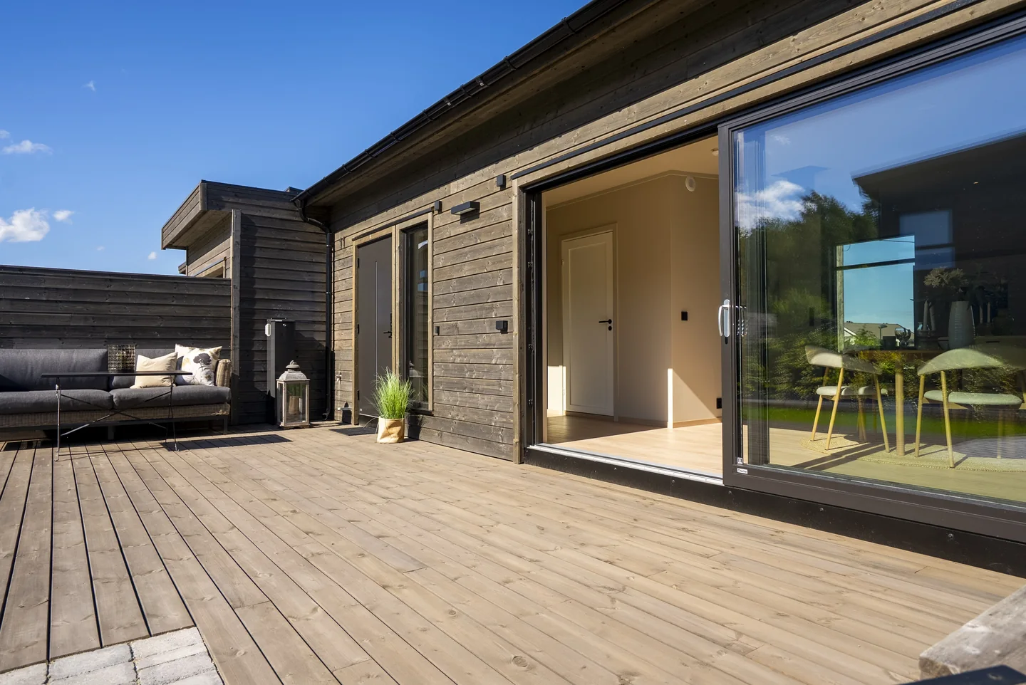 Terrassen ved stuen med åpen skyvedør til boligen.